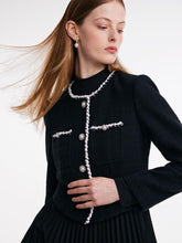 A woman with pearl earrings wears a vintage suit.